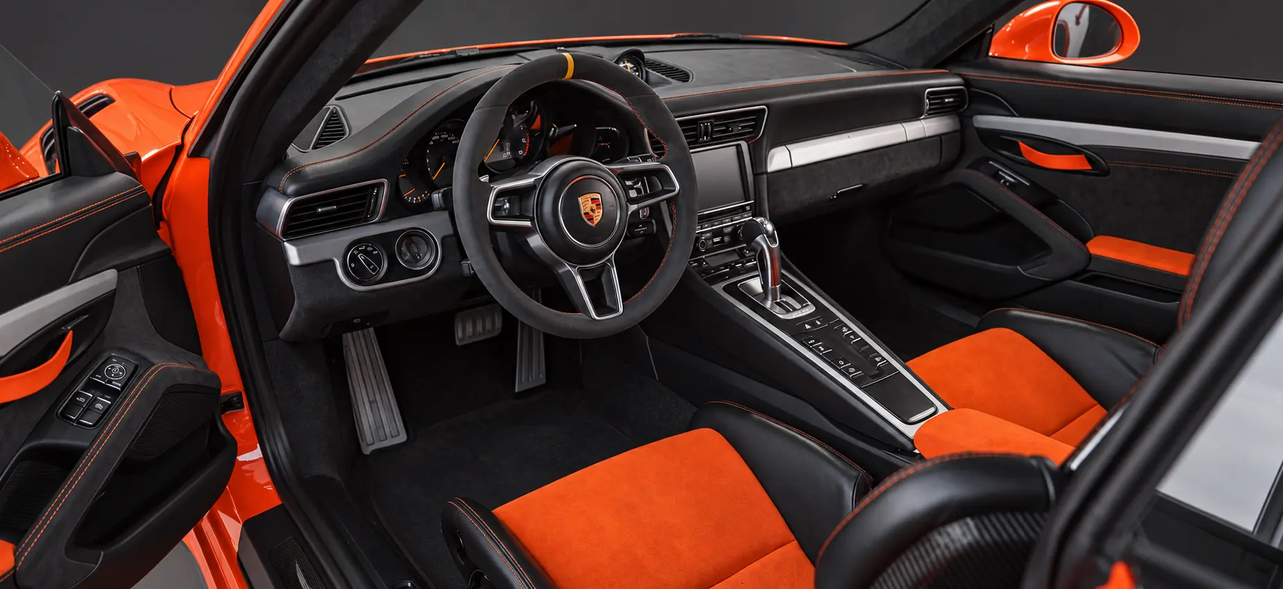 Habitáculo del Porsche naranja: volante, consola, Alcantara y costuras