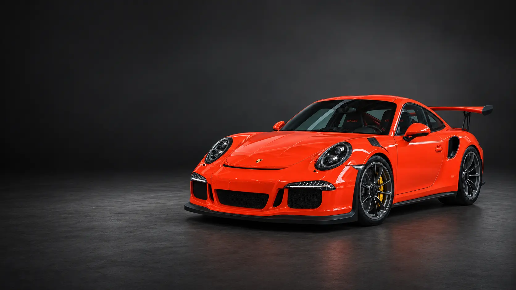Porsche 911 GT3 RS naranja completo, situado a la derecha sobre un piso de estudio continuo